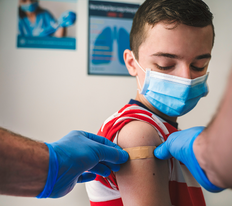 Une jeune personne portant un masque et se faisant vacciner contre la COVID-19