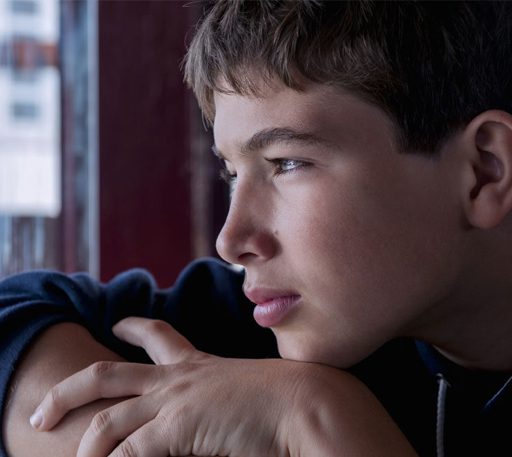 Un·e adolescent·e regardant la fenêtre en pleurant la perte d'un·e proche par suicide